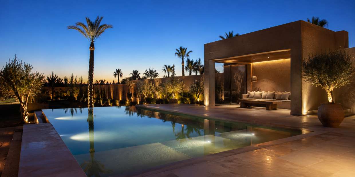 Piscine terminée et éclairée la nuit avec pool house