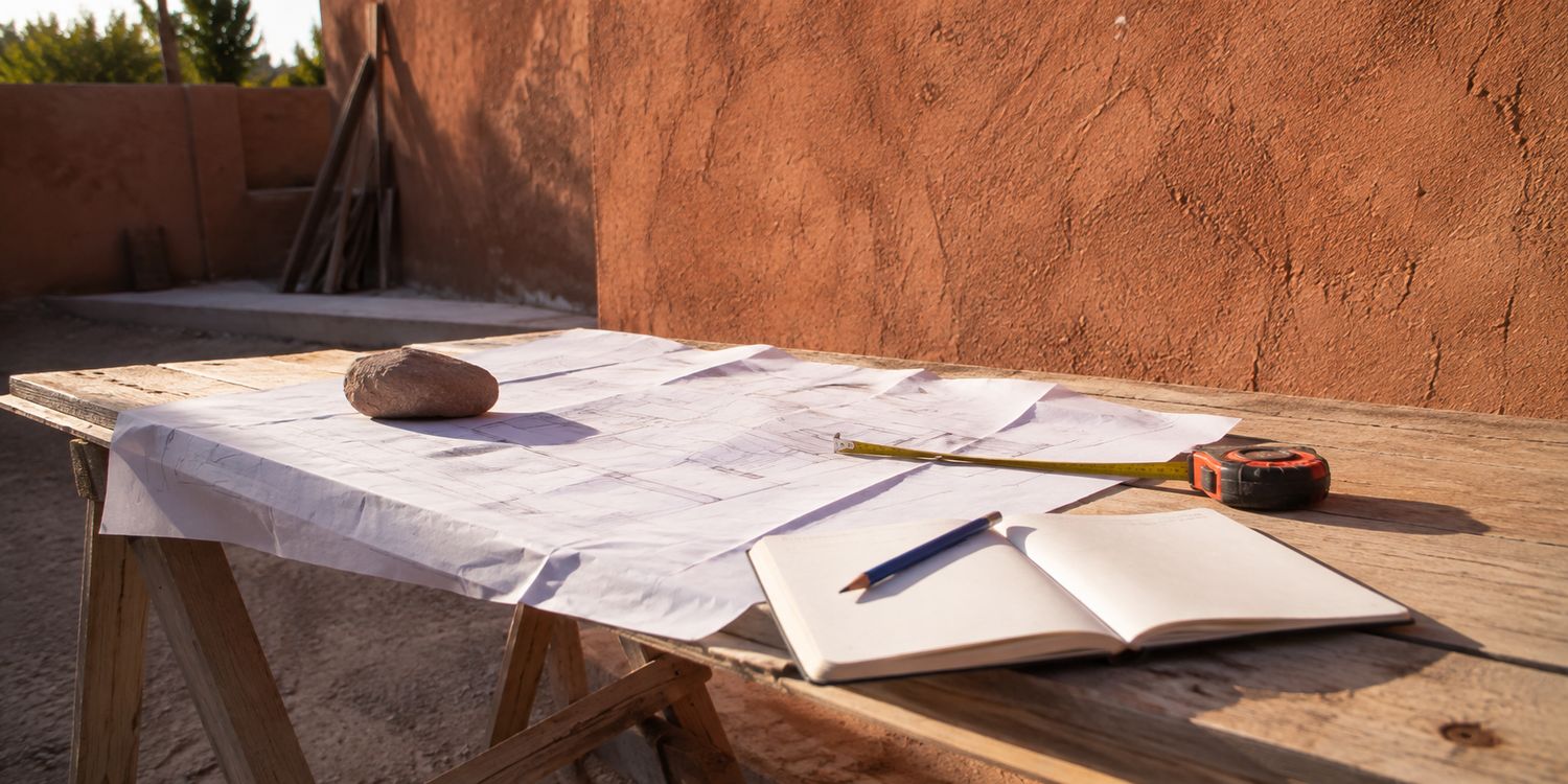 Plans de chantier dépliés sur une table en bois à Marrakech